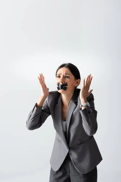 Emotional businesswoman with scotch tape on mouth gesturing isolated on white — Stock Photo