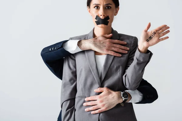 Businessman molesting businesswoman with scotch tape on mouth showing hand with me too lettering isolated on white — Stock Photo