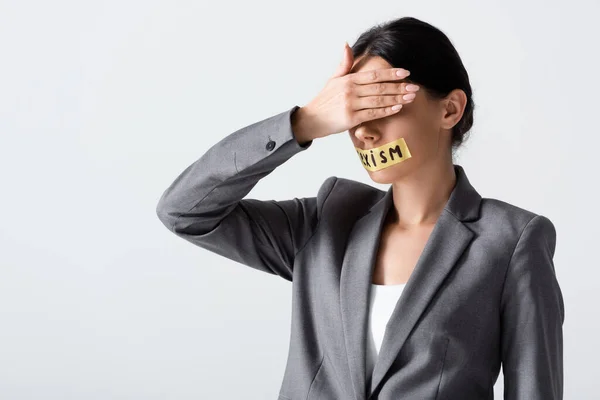 Geschäftsfrau mit Sexismus-Schriftzug auf Klebeband verdeckt Augen auf weißem Grund — Stockfoto