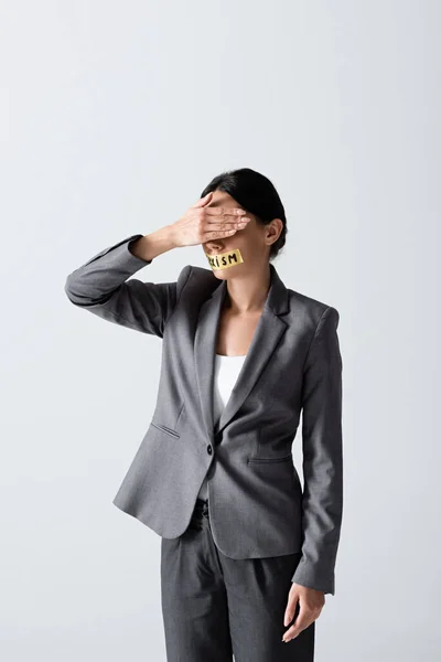 Businesswoman with sexism lettering on duct tape covering eyes isolated on white — Stock Photo