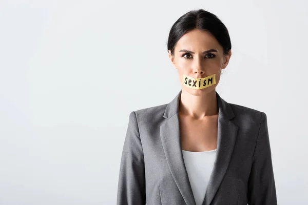 Femme d'affaires avec lettrage sexisme sur ruban adhésif regardant la caméra isolée sur blanc — Photo de stock