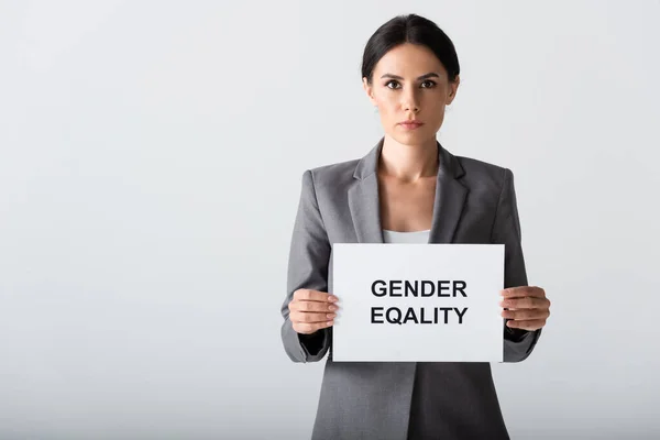 Mulher de negócios atraente segurando cartaz com letras igualdade de gênero isolado no branco — Fotografia de Stock