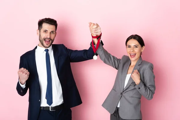 Empresário animado e empresária segurando medalha de ouro e gesticulando em rosa, conceito de igualdade de gênero — Fotografia de Stock