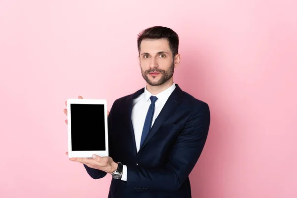 Handsome businessman holding digital tablet with blank screen on pink — Stock Photo