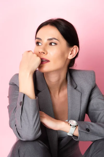 Nachdenkliche Geschäftsfrau im Anzug schaut vereinzelt auf rosa — Stockfoto