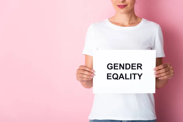 Vista cortada da mulher em t-shirt branca segurando cartaz com igualdade de gênero lettering em rosa — Fotografia de Stock