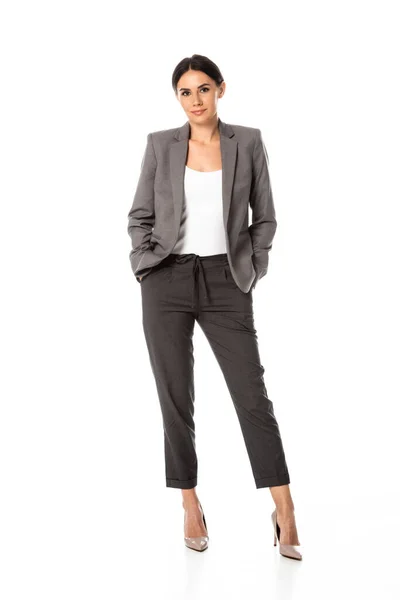 Young businesswoman in suit standing with hands in pockets isolated on white — Stock Photo