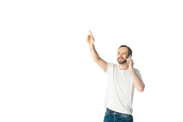 Sonriente hombre hablando en teléfono inteligente con la mano levantada aislado en blanco - foto de stock