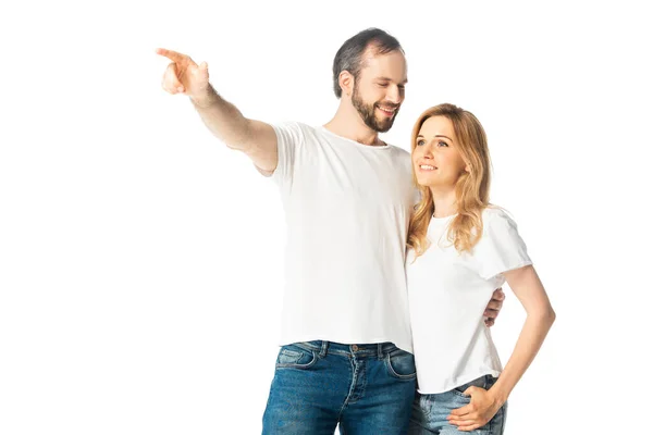 Cheerful man embracing wife and pointing with finger away isolated on white — Stock Photo