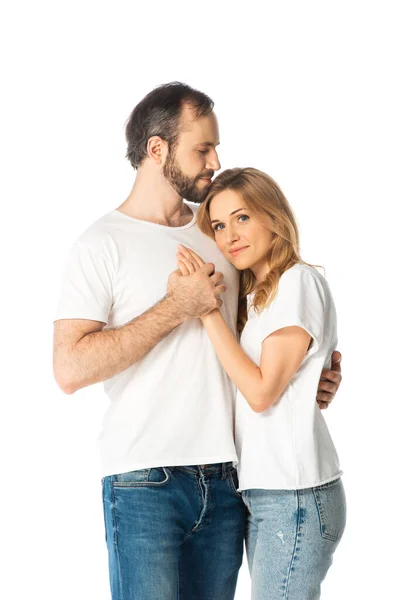 Pareja adulta en camisetas blancas abrazando y tomándose de las manos aisladas en blanco - foto de stock