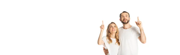 Cheerful adult couple in white t-shirts pointing with fingers up isolated on white, panoramic shot — Stock Photo