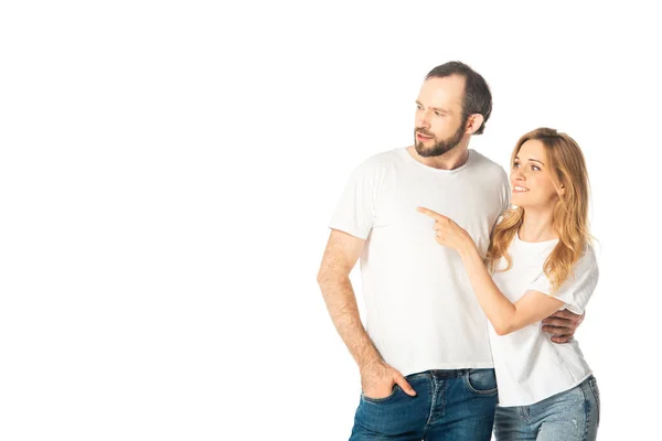 Fröhliches erwachsenes Paar in weißen T-Shirts, das mit dem Finger zur Seite zeigt — Stockfoto