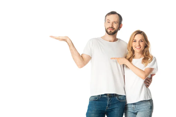 Sorridente coppia adulta in t-shirt bianche che punta con mano e dito a parte isolato su bianco — Foto stock