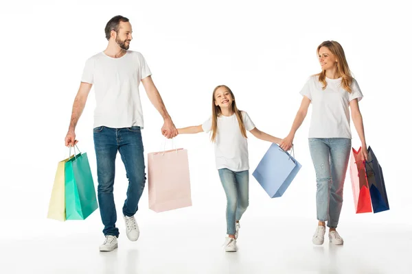 Fröhliche Familienwanderung mit bunten Einkaufstüten und Händchen haltend auf weißem Grund — Stockfoto
