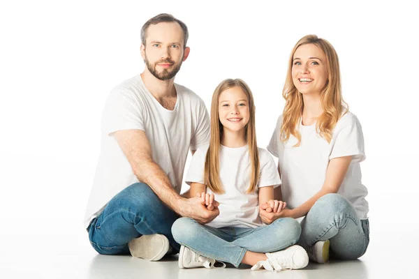 Glückliche Familie, die mit überkreuzten Beinen auf dem Boden sitzt und die Hände isoliert auf weiß hält — Stockfoto