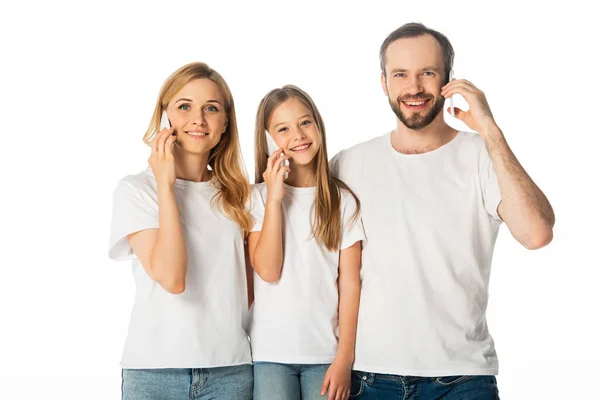 Улыбающаяся семья в белых футболках разговаривает на смартфонах изолированных на белом — стоковое фото