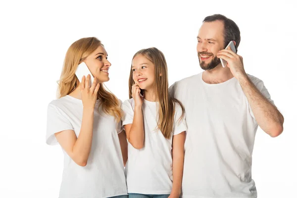 Família sorridente em camisetas brancas falando em smartphones isolados em branco — Fotografia de Stock