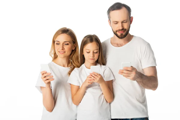 Семья в белых футболках с использованием смартфонов, изолированных на белом — стоковое фото