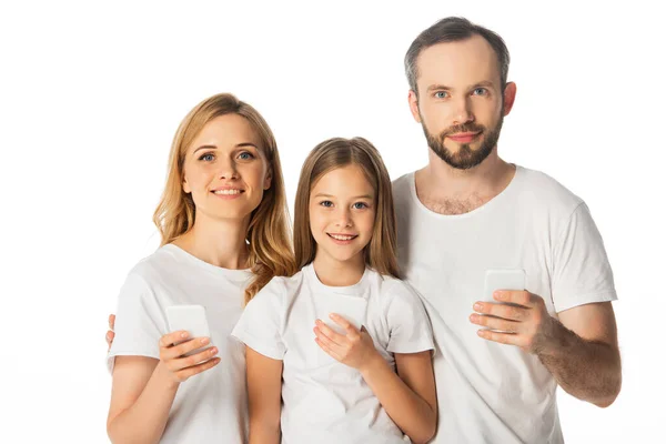 Família sorridente em camisetas brancas usando smartphones isolados em branco — Fotografia de Stock