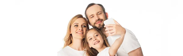 Счастливая семья в белых футболках делает селфи на смартфоне изолированный на белом, панорамный снимок — стоковое фото