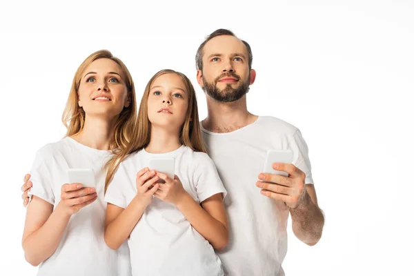 Familia en camisetas blancas usando teléfonos inteligentes aislados en blanco - foto de stock