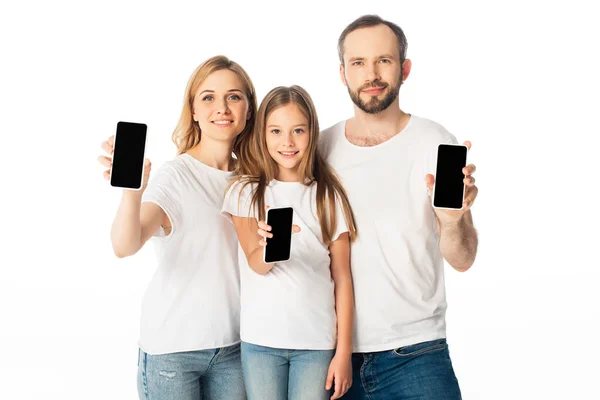 Famiglia sorridente in t-shirt bianche che mostrano smartphone con schermi vuoti isolati su bianco — Foto stock