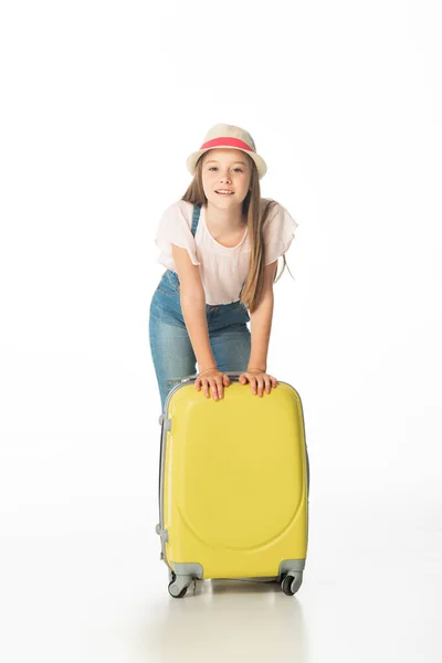Весела дівчина в капелюсі біля жовтого сумки для подорожей ізольована на білому — стокове фото