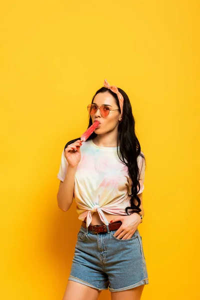 Elegante estate bruna ragazza mangiare gelato su sfondo giallo — Foto stock