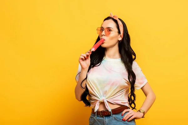 Стильна літня брюнетка дівчина їсть морозиво на жовтому фоні — стокове фото
