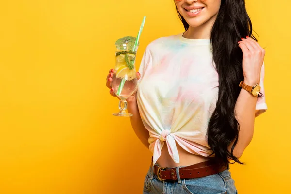 Vue recadrée de souriant élégant été fille brune avec cocktail rafraîchissant sur fond jaune — Photo de stock