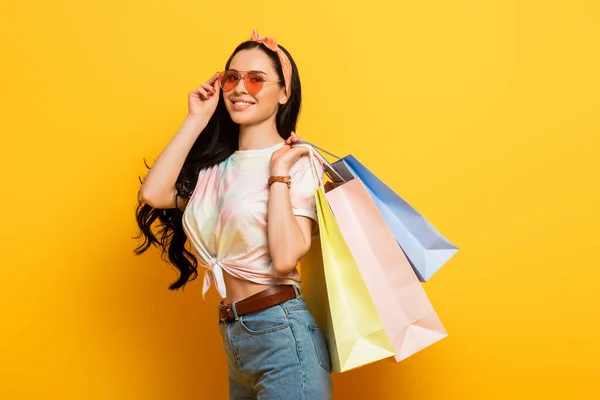 Sorrindo elegante verão menina morena com sacos de compras no fundo amarelo — Fotografia de Stock