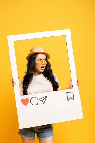 Shocked brunette girl in summer outfit posing in social network frame on yellow background — Stock Photo