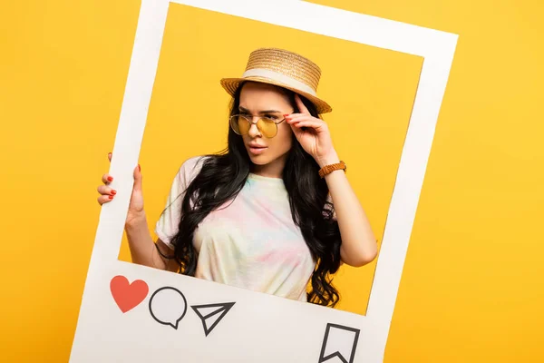 Серйозна брюнетка дівчина в літньому вбранні позує в соціальній мережі на жовтому фоні — стокове фото