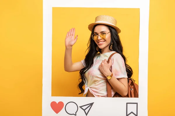Felice ragazza bruna in abito estivo agitando mano nella cornice del social network su sfondo giallo — Foto stock