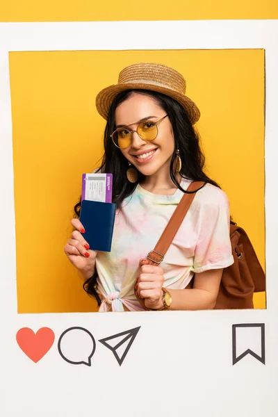 Heureuse fille brune en tenue d'été tenant billet d'avion dans le cadre du réseau social sur fond jaune — Photo de stock