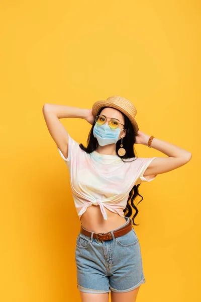 Brunette girl in summer outfit and medical mask on yellow background — Stock Photo