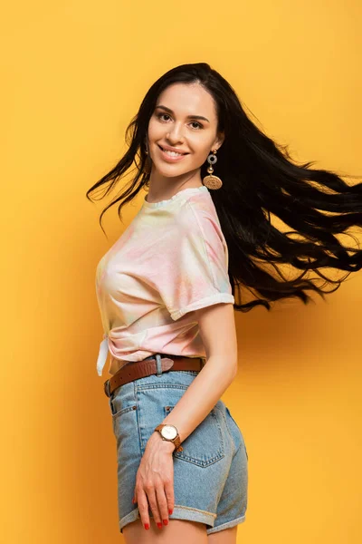 Menina morena feliz girando em torno de fundo amarelo — Fotografia de Stock