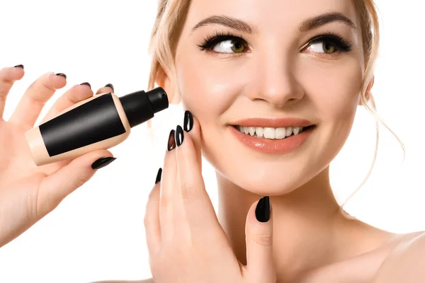 Smiling naked beautiful blonde woman with makeup and black nails holding face foundation isolated on white — Stock Photo