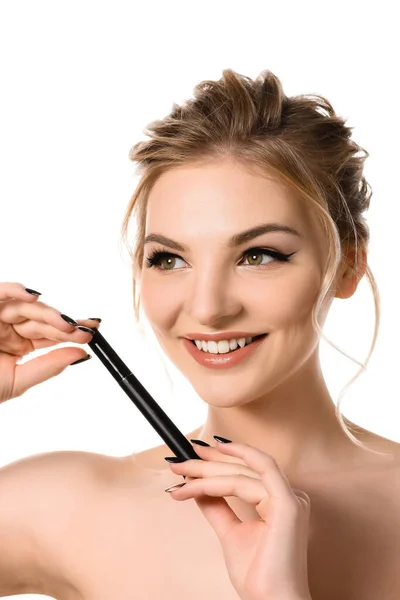 Sonriente mujer rubia hermosa desnuda con maquillaje y uñas negras sosteniendo rímel aislado en blanco - foto de stock