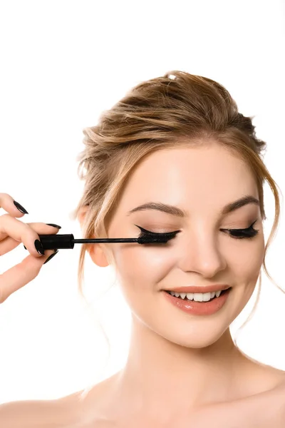 Sorrindo nu bela mulher loira com maquiagem e unhas pretas aplicando rímel isolado no branco — Fotografia de Stock