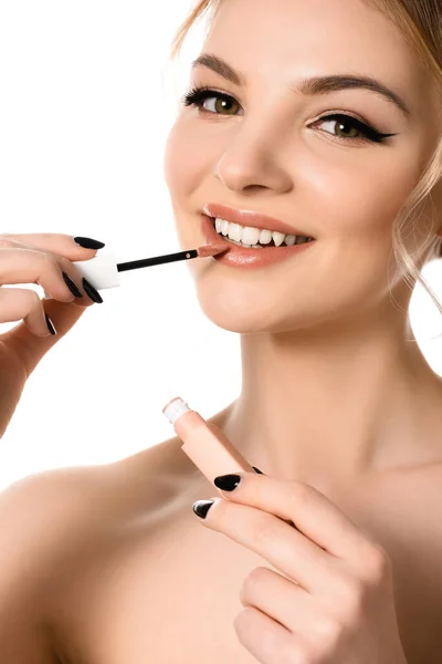 Smiling naked beautiful blonde woman with makeup and black nails applying beige lip gloss isolated on white — Stock Photo