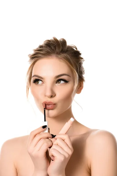 Mujer rubia hermosa desnuda con maquillaje y uñas negras aplicando brillo de labios beige aislado en blanco - foto de stock