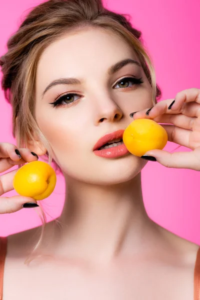 Elegant beautiful blonde woman holding apricots isolated on pink — Stock Photo