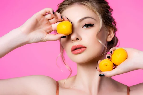 Elegant beautiful blonde woman holding apricots isolated on pink — Stock Photo