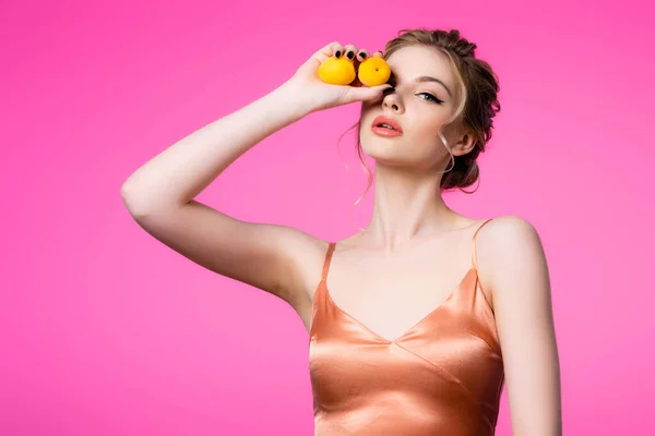 Elegant beautiful blonde woman in silk dress holding apricots isolated on pink — Stock Photo