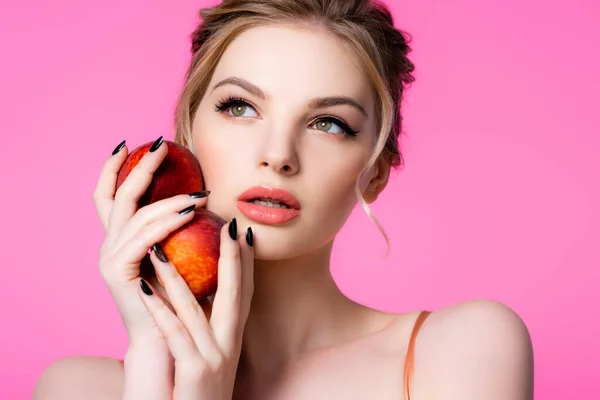 Elegante bella donna bionda che tiene le pesche isolate sul rosa — Stock Photo