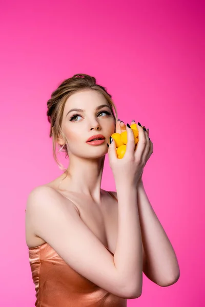 Dreamy elegant beautiful blonde woman in silk dress holding ripe apricots isolated on pink — Stock Photo