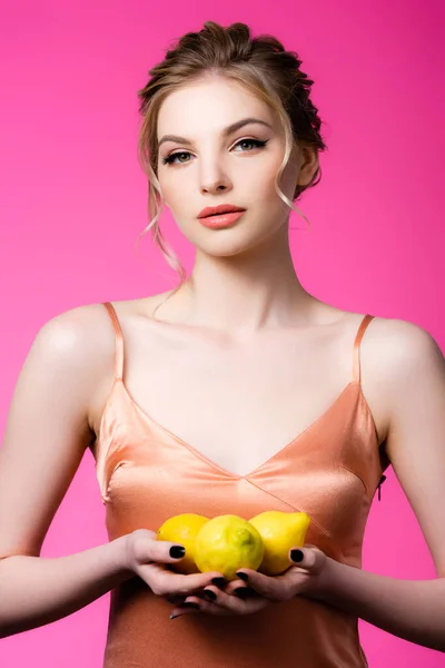 Elegante bella donna bionda in possesso di limoni maturi isolati su rosa — Foto stock