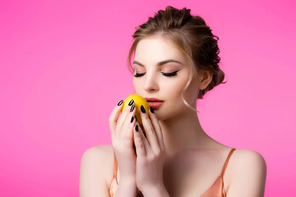 Элегантная красивая блондинка с закрытыми глазами держа спелый лимон изолирован на розовый — стоковое фото