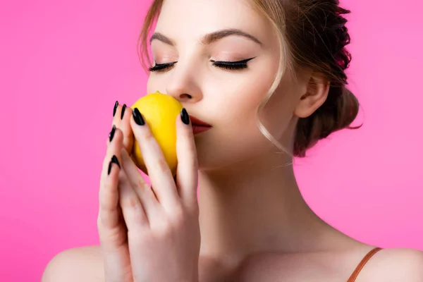 Hermosa mujer rubia oliendo limón maduro aislado en rosa - foto de stock